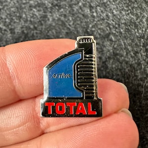 May include: A silver metal pin with a blue and black oil bottle design. The bottle has the word "Activa" on it and the word "TOTAL" in red letters at the bottom.
