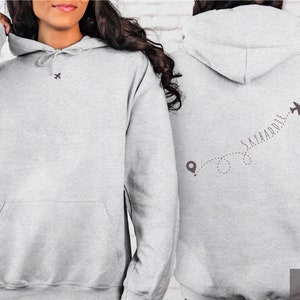 May include: A gray hoodie with a small airplane graphic on the front and a larger airplane graphic with the text "SKYBADDIE" on the back. The hoodie is made of a soft, comfortable material and has a drawstring hood.