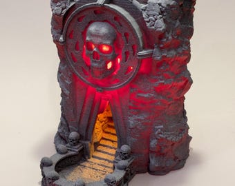 May include: A gray, 3D-printed castle-like structure with a skull design and red glowing lights. The structure features a skull-shaped emblem, a staircase, and skull-shaped accents. The overall design has a gothic or fantasy theme.