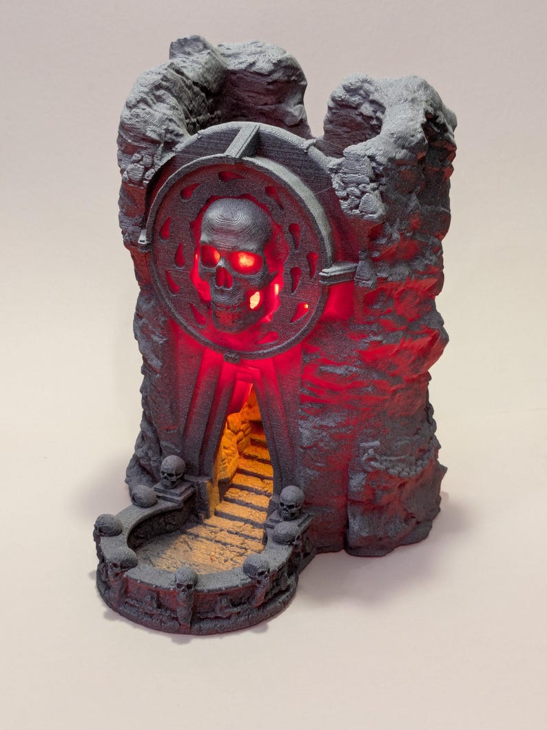 Puede incluir: Una estructura gris impresa en 3D con forma de castillo con un dise&ntilde;o de calavera y luces rojas brillantes. La estructura presenta un emblema en forma de calavera, una escalera y detalles en forma de calavera. El dise&ntilde;o general tiene un tema g&oacute;tico o de fantas&iacute;a.