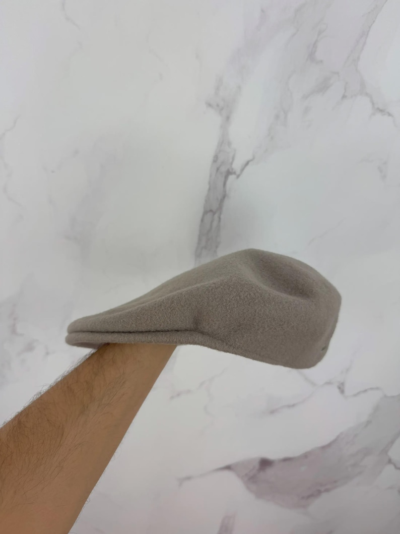 May include: A tan-colored, fleece newsboy cap. The hat has a rounded crown and a small, stiff brim. The cap is made of a soft, textured material. The hat is a classic style, suitable for various outfits.