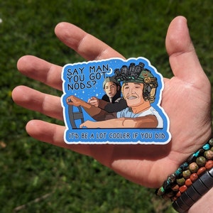 May include: A blue sticker with a cartoon image of two people in a car. The text on the sticker says "Say man, you got nods? It'd be a lot cooler if you did."