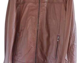 May include: A brown leather jacket with a zipper closure and two zippered pockets on the front. The jacket has a stand-up collar and long sleeves.