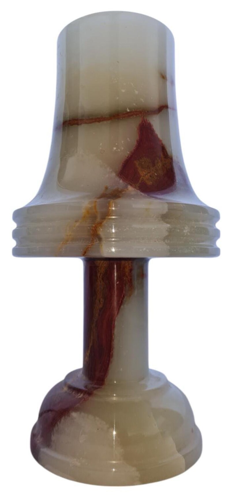 May include: A decorative onyx candle holder with a flared top and a round base. The candle holder features a mix of white, brown, and red hues, creating a marbled effect. The design includes a cylindrical stem and a tiered accent.