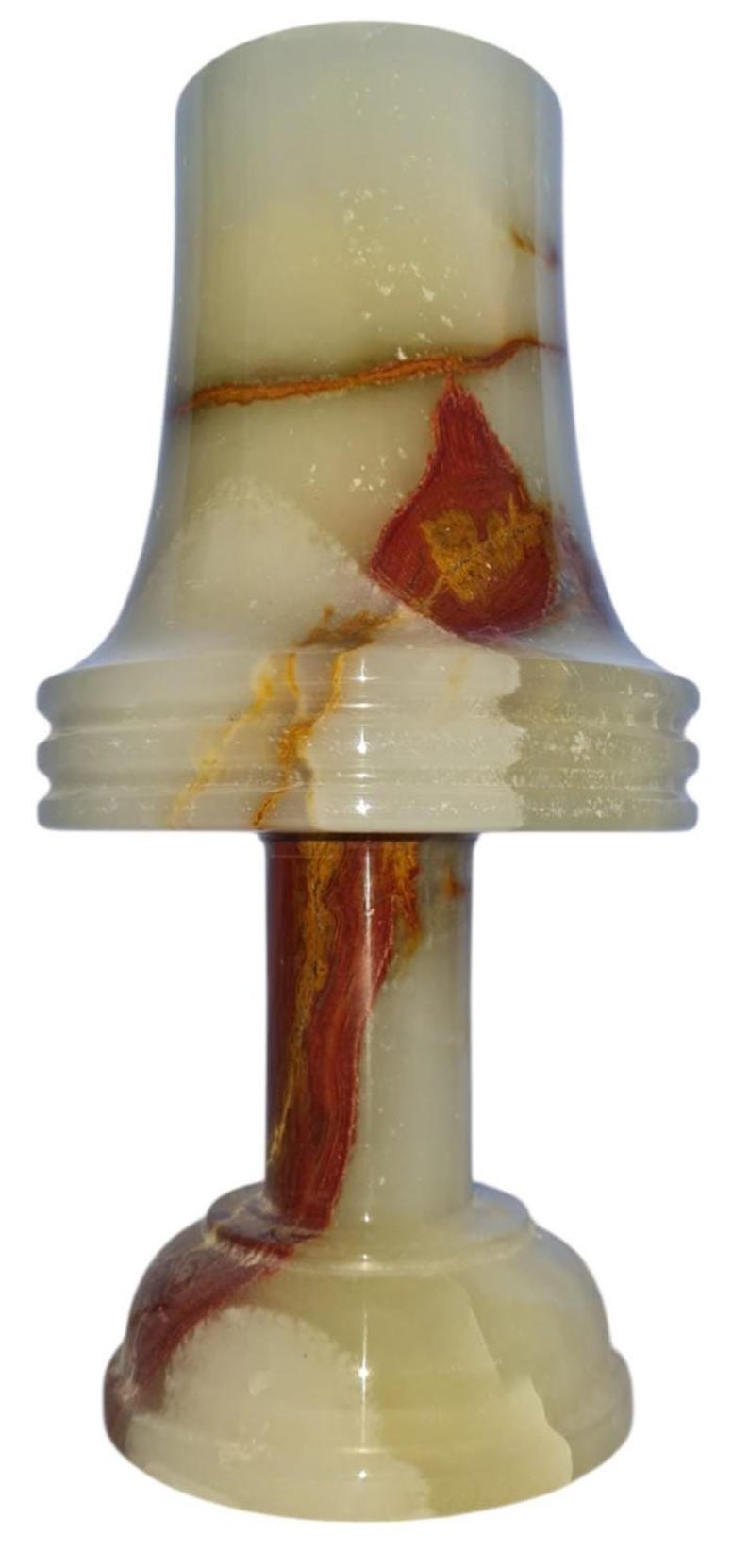 May include: A decorative onyx lamp with a flared top and a round base. The lamp features a cream and green color scheme with red and gold veining throughout. The lamp is approximately 7 inches tall.