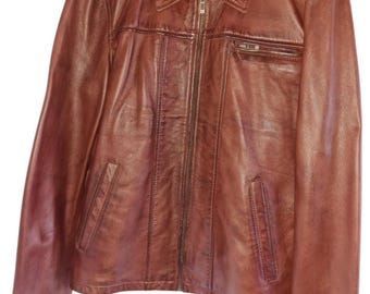 May include: A brown leather jacket with a zipper closure and a collar. The jacket has two pockets on the front and a label that says "SAM" on the left side of the chest.