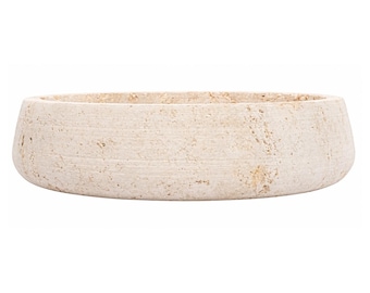 May include: A round, shallow basin made of beige, porous stone with a textured, natural surface. The vessel features a thick, uniform rim and a wide, open interior, showcasing the organic, pitted appearance of the raw, light-colored material.