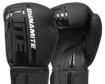 Puede incluir: Un par de guantes de boxeo negros con la marca "Dynamite" en blanco en la parte delantera y una muñequera negra con la misma marca.