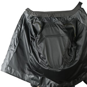 May include: Black motorcycle jacket interior with a mesh lining and multiple pockets. The jacket is open, revealing the inside construction and design. The interior features a zippered pocket and a breathable mesh material.