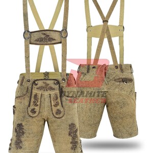 May include: Tan leather lederhosen with suspenders. The shorts feature decorative embroidery and button details. The suspenders are a lighter tan color and attach to the shorts with metal hardware. The lederhosen are displayed on a white background.