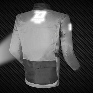 May include: A gray motorcycle jacket with black accents and reflective logos. The jacket features the text "DYNAMITE GEAR" on the back and a smaller logo on the sleeve. It has a black lower pocket and yellow stitching details.