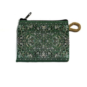May include: A green zippered pouch with a gold tassel. The pouch has a patterned design that resembles a rug.