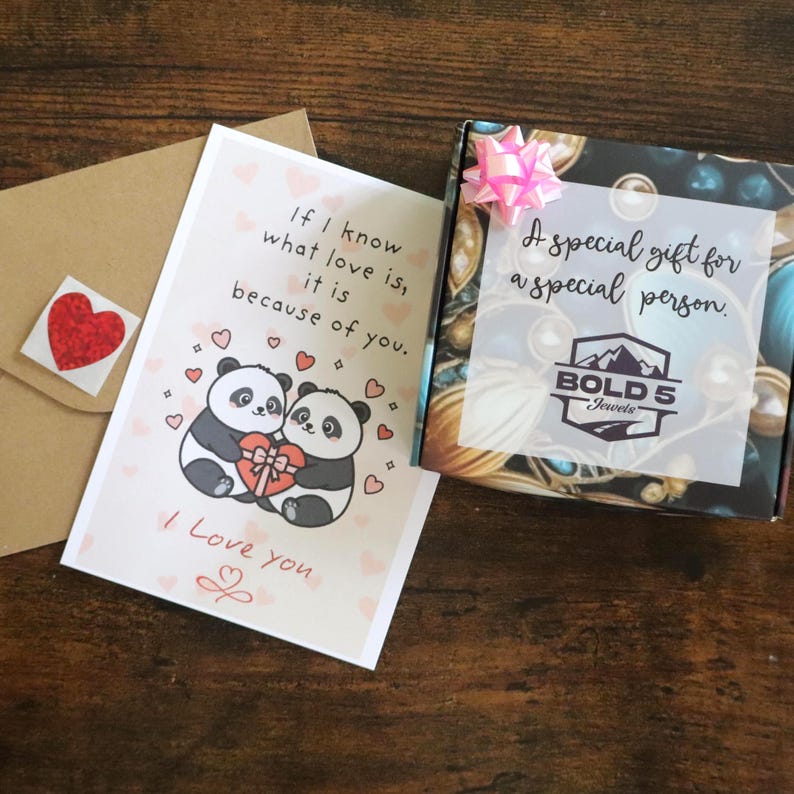 以下が含まれることがあります： ピンクのリボンが付いた正方形のギフトボックスには「A special gift for a special person」という文字とBold 5 Jewelsのロゴがあり、ハートを持った2匹のパンダと「If I know what love is, it is because of you.」という文字が書かれたグリーティングカードが添えられています。
