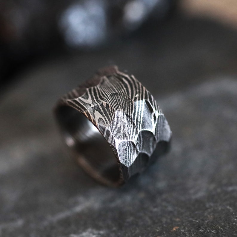 Peut inclure: Gros plan d'une bague argent&eacute;e textur&eacute;e. La bague pr&eacute;sente un motif unique et un design &agrave; facettes. La bague semble &ecirc;tre en m&eacute;tal, probablement un bijou.