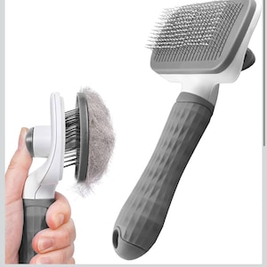 May include: A gray and white pet grooming brush with a textured handle. The brush has metal bristles and a button to remove collected fur. The image shows the brush with and without collected fur.