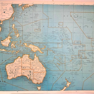 May include: A vintage map of Oceania, featuring Australia, New Zealand, and surrounding islands. The map, in shades of blue, tan, and brown, includes geographical details, place names, and the Rand McNally logo. The Mercator projection is used.