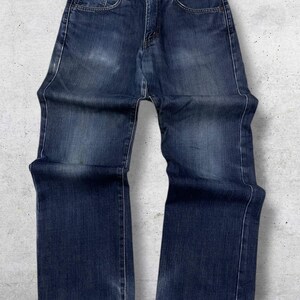 May include: Dark wash denim jeans with a classic five-pocket design. The jeans have a straight leg cut and are made of a durable denim fabric. The jeans feature a button and zipper closure and are suitable for everyday wear.