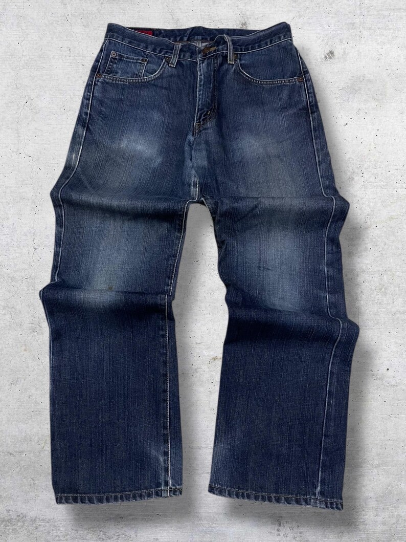 May include: Dark wash denim jeans with a classic five-pocket design. The jeans have a straight leg cut and are made of a durable denim fabric. The jeans feature a button and zipper closure and are suitable for everyday wear.