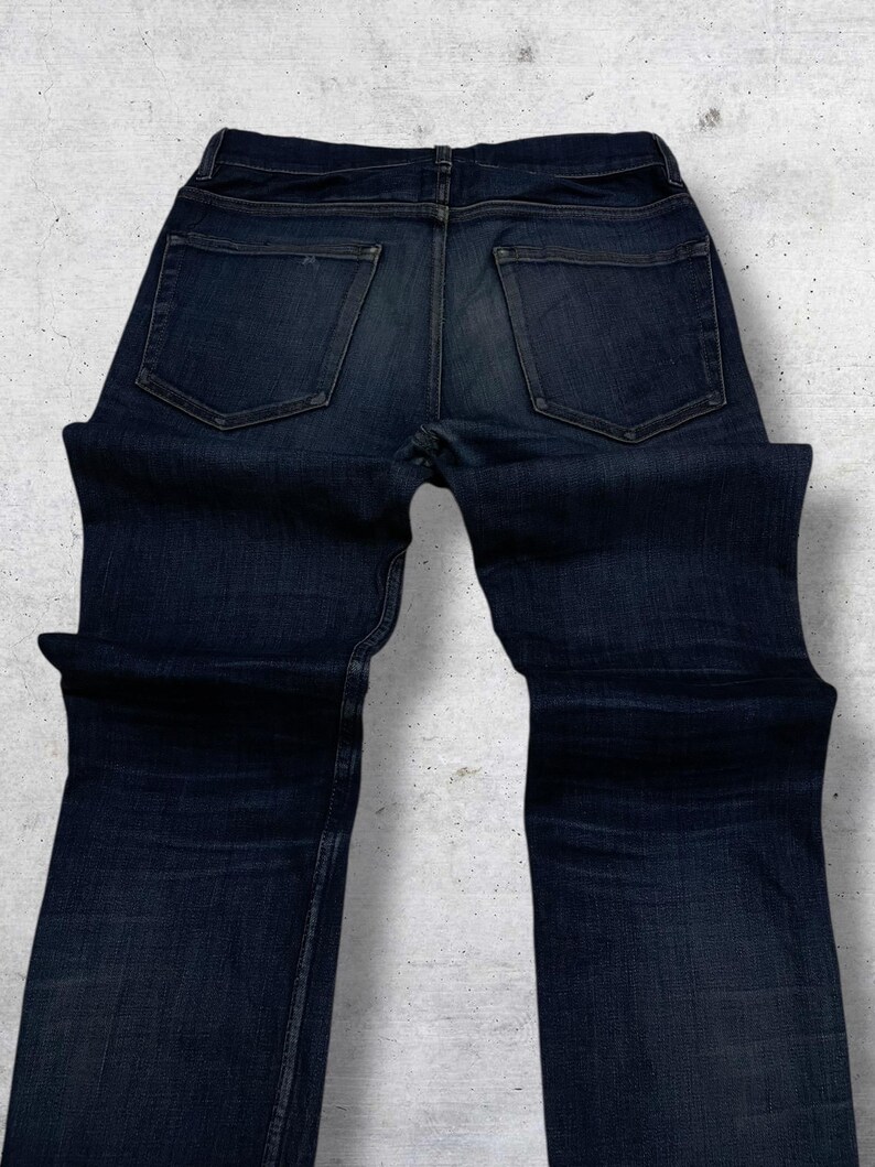 Op de afbeelding: Een witte keramische mok met een zwarte handgreep en de tekst "But First, Coffee" in een zwarte, vette letter. De mok is waarschijnlijk 325 ml groot, perfect voor een ochtenddrankje.