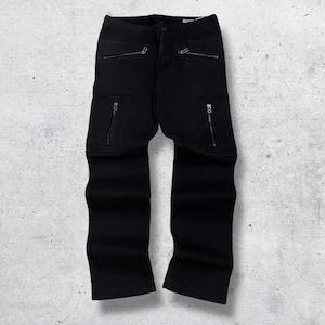 May include: Black cargo pants with multiple zippered pockets and a straight leg design. The pants have zippers at the front pockets and on the cargo pockets. The pants are displayed on a light gray background.