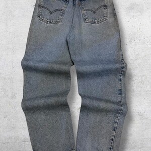 May include: Light blue denim jeans with classic five-pocket styling. Features a faded wash and the iconic Levi's brand patch on the back waistband. The jeans have a straight leg fit and are designed for everyday wear.