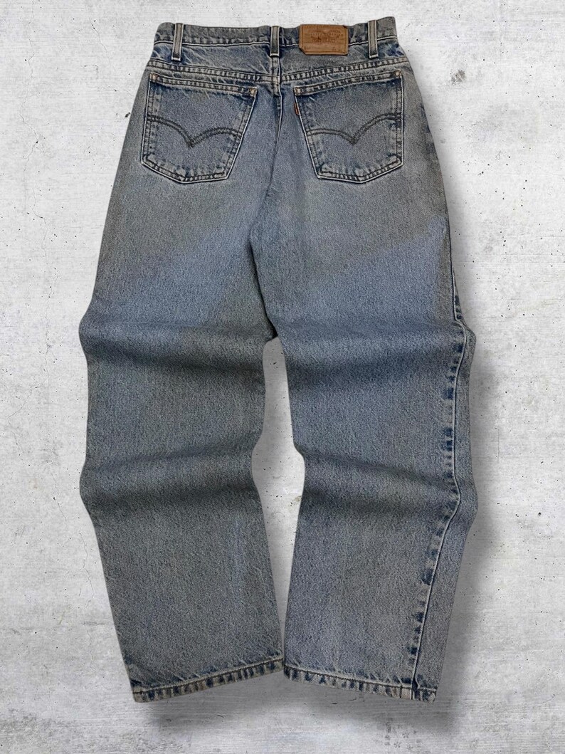 May include: Light blue denim jeans with classic five-pocket styling. Features a faded wash and the iconic Levi's brand patch on the back waistband. The jeans have a straight leg fit and are designed for everyday wear.