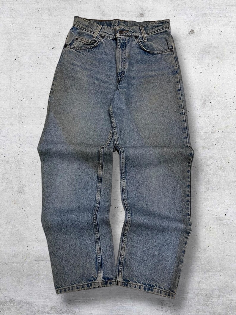 May include: Light blue denim jeans with a classic five-pocket design. The jeans have a straight leg cut and a faded wash, giving them a vintage look. The jeans are made of durable denim material and feature a button and zipper closure.