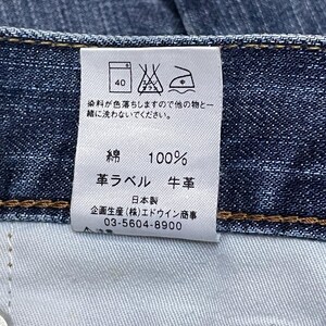 May include: Close-up of a denim jeans label with Japanese text and care symbols. The label indicates 100% cotton, leather, and washing instructions. The label also includes a phone number.