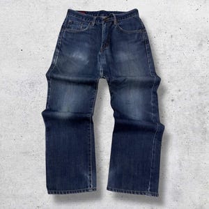 May include: A pair of dark wash denim jeans. The jeans have a classic five-pocket design, a button and zipper closure, and a straight leg fit. The denim has some fading and wear, giving them a vintage look.