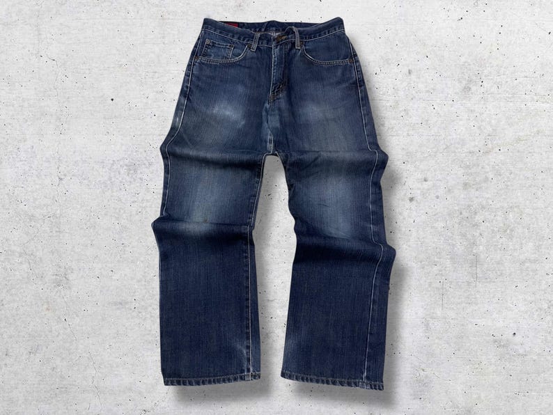 May include: A pair of dark wash denim jeans. The jeans have a classic five-pocket design, a button and zipper closure, and a straight leg fit. The denim has some fading and wear, giving them a vintage look.