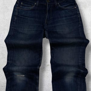 Op de afbeelding: Donkerblauwe denim jeans met een beschadigde knie. De jeans hebben een klassiek ontwerp met vijf zakken en een knoop- en ritssluiting. De merknaam "Acne Studios" is zichtbaar op de tailleband.