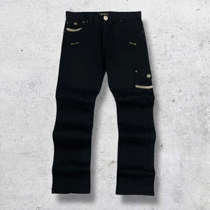 以下が含まれることがあります： ベージュのアクセントが付いた黒のデニムカーゴパンツ。パンツには、側面のカーゴポケットや装飾的なステッチなど、複数のポケットが付いています。ボタンとジッパーで開閉するクラシックな5ポケットデザインです。