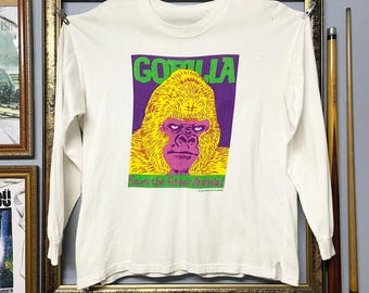 May include: White long-sleeve shirt featuring a gorilla graphic. The graphic includes the word "GORILLA" in green, a purple background, and a yellow gorilla face. The text "Save the Great Apes!" is also included.