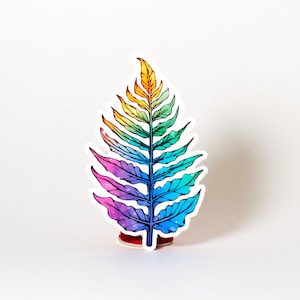 May include: A rainbow-colored fern leaf sticker with a white outline. The sticker is on a white background.