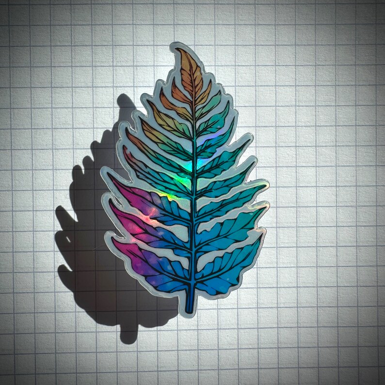 May include: A holographic fern leaf sticker with a rainbow gradient of pink, blue, and green.