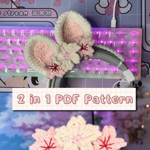 Könnte beinhalten: Ein Paar gehäkelte Kopfhörerbezüge mit einem rosa-weißen Kirschblütenmuster. Die Bezüge sind auf einem Kopfhörer gezeigt. Der Text "2 in 1 PDF Pattern" ist im Bild sichtbar.