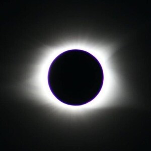 May include: A celestial image of a solar eclipse. A dark, circular object is centered, surrounded by a bright, white corona. The background is a deep black, creating a dramatic contrast.