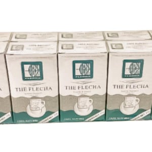 May include: A collection of six boxes of "THE FLECHA" coffee. Each box is white with a teal and gray design featuring a cup and saucer. The boxes are arranged side by side.