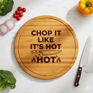Puede incluir: Una tabla de cortar redonda de madera con el texto "CHOP IT LIKE IT'S HOT" y un gráfico de cuchillo. Un cuchillo de chef de acero inoxidable con mango marrón oscuro está a la derecha. Se ven brócoli, tomates rojos y pimiento amarillo.