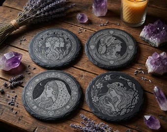 May include: Four round slate coasters with engraved goddess designs, surrounded by lavender, crystals, and a lit candle. The coasters feature detailed illustrations of women with floral and celestial elements.
