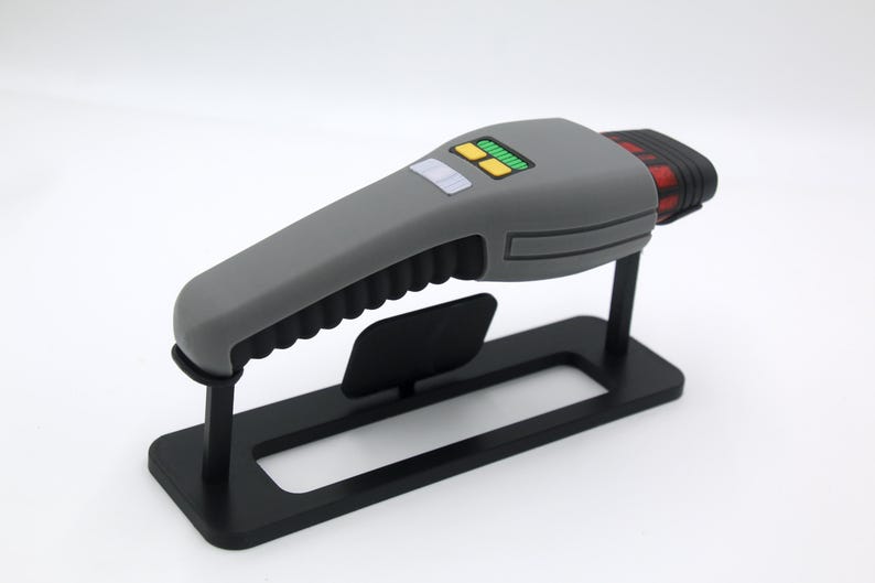 K&ouml;nnte beinhalten: Ein graues und rotes Handger&auml;t mit einem schwarzen St&auml;nder. Das Ger&auml;t hat einen strukturierten Griff und ein kleines Display mit gr&uuml;nen Lichtern.