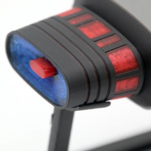 K&ouml;nnte beinhalten: Nahaufnahme eines schwarzen und grauen Raumschiffmodells mit roten und blauen Details. Das Modell verf&uuml;gt &uuml;ber ein detailliertes Cockpit und ein elegantes Design.