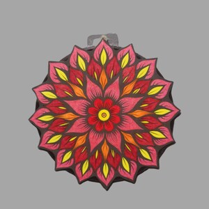 May include: A round, colorful mandala design with a pink, red, and yellow flower in the center. The mandala is made of overlapping petals in shades of red, orange, and yellow.