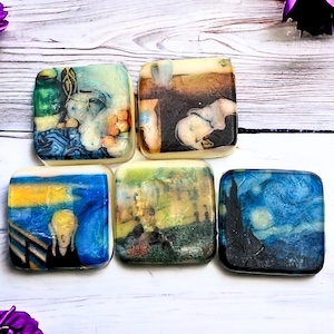 May include: Six square-shaped soaps with different famous paintings printed on them. The soaps are white and the paintings are in various colours, including blue, yellow, green, and black.