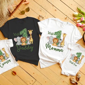 Pu&ograve; includere: Una collezione di magliette familiari abbinate e un body a tema giungla. Le magliette sono nere e bianche, e il body &egrave; bianco. Ogni maglietta presenta il numero uno, animali della giungla e le parole "Daddy", "Momma", "Cousin" e "Wild One".