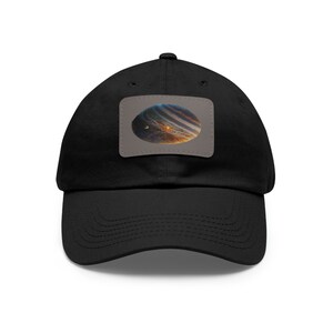 May include: A black baseball cap with a patch featuring a colorful image of a planet with rings.