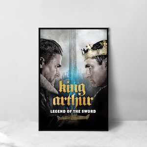 May include: A movie poster for the film "King Arthur: Legend of the Sword". The poster features two men facing each other, one with a crown and the other with a beard. The background is a dark, stormy sky with a sword in the center.