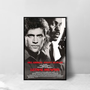 May include: A framed movie poster for "Lethal Weapon" featuring Mel Gibson and Danny Glover. The poster has a black border and a vintage design with red and white text. Glover is holding a gun.