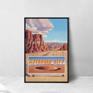 Puede incluir: Un cartel de estilo vintage que anuncia "Asteroid City" con una vista panorámica de un paisaje desértico, formaciones rocosas rojas y un gran cráter en primer plano. El cartel presenta un cielo azul con nubes blancas y un camino que se extiende hacia la distancia.