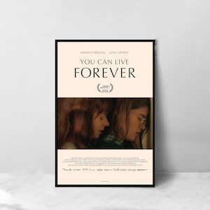 May include: A movie poster for the film "You Can Live Forever" featuring two young women embracing. The poster is in a black frame and has a peach background with the film title in black text. The poster also includes the names of the actors, Anwen O'Driscoll and June Laporte, and the text "Tribeca Film Festival 2022".